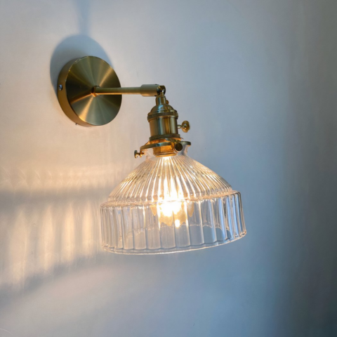 Elegante y moderno aplique de cristal con base dorada y pantalla de cristal transparente, con luz blanca