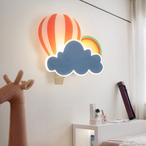 En la pared del dormitorio de un niño, en el centro de la imagen puede ver un aplique con forma de nube, globo aerostático y arco iris para el dormitorio de un niño. En la parte inferior izquierda de la imagen hay una cabeza de juguete de una jirafa rosa.