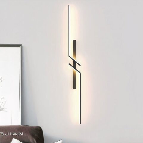 Aplique negro de espejo geométrico colgado de una pared blanca.