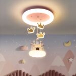 Hay una lámpara de araña en el techo con un castillo y coronas. Perfecto para el dormitorio de una niña.
