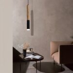 Colgante de madera LED en forma de tubo negro y beige, suspendido sobre una mesa de centro