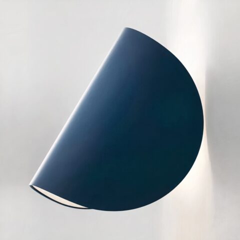Aplique azul en forma de círculo doblado hacia la pared, como un taco. La bombilla está encendida y la pared es blanca.