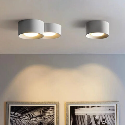 Moderna lámpara LED de diseño cilíndrico minimalista y foco empotrado en blanco, fijada al techo e iluminada, en un salón.
