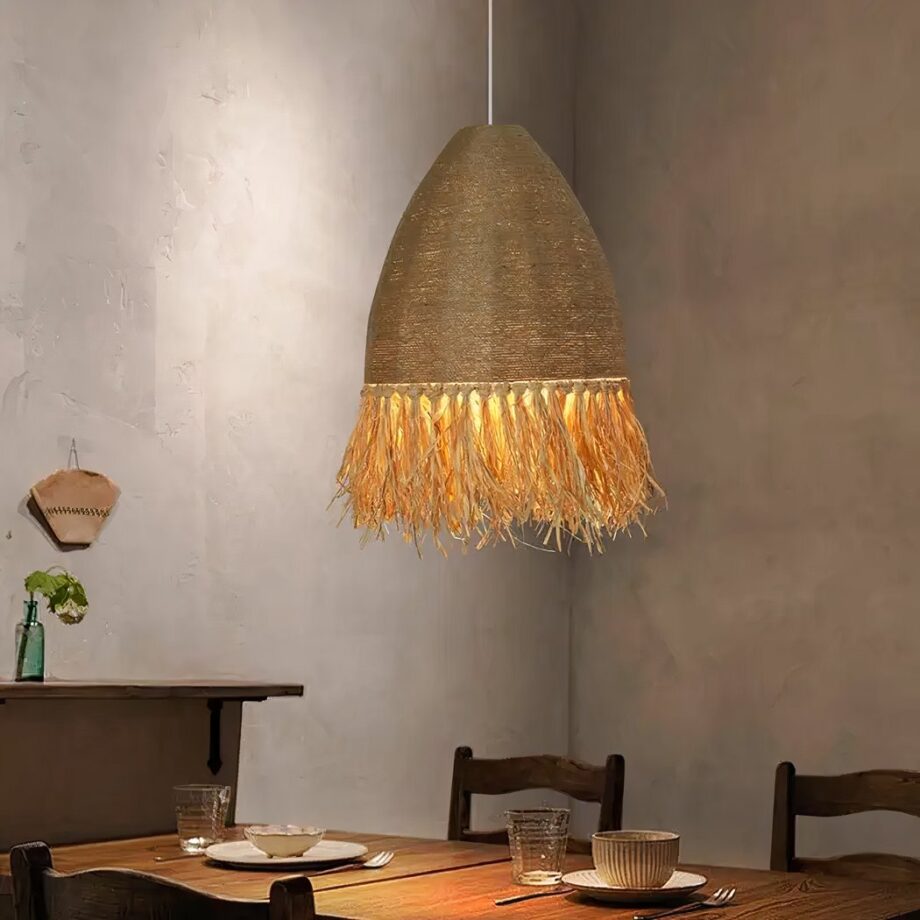 Araña de paja y cuerda hecha a mano suspendida e iluminada sobre una mesa de comedor preparada para la cena.