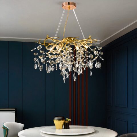 Una gran araña moderna y majestuosa con ramas de cristal y colgantes suspendida del techo y encima de una mesa de comedor.