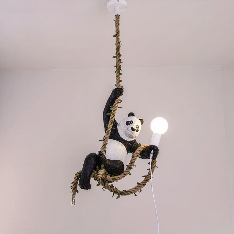 Suspensión con un panda en una cuerda Suspensión con cuerda de cáñamo entrelazada con follaje. Un panda cuelga de su pata delantera derecha, la cuerda pasa por sus patas traseras y sujeta una bombilla en su pata delantera izquierda con parte de la cuerda.