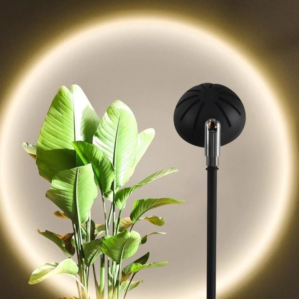 Cabezal negro encendido junto a una planta proyectando un anillo de luz cálida