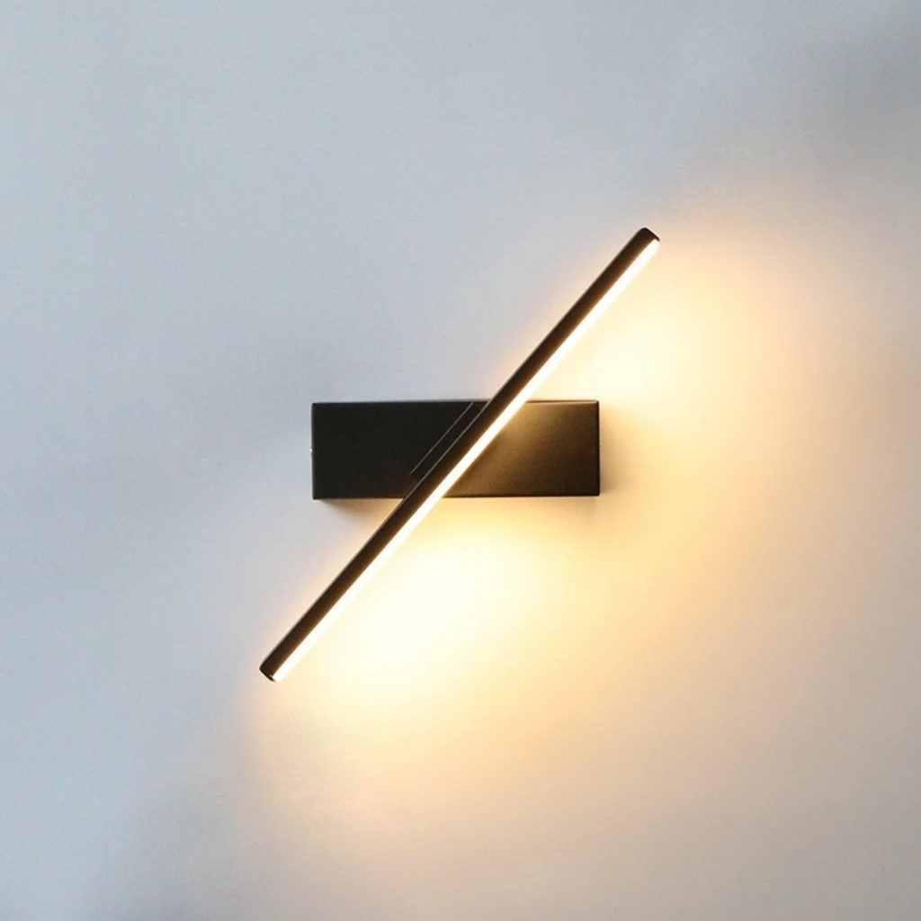 Aplique LED negro con barra de luz orientable sobre pared blanca